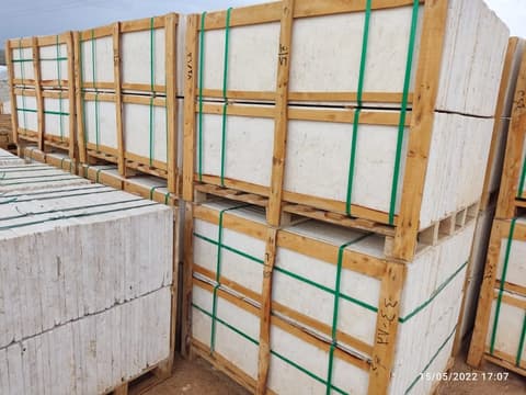 طبليات بلاط حجر كريمي مربوطة بأشرطة خضراء في المستودع